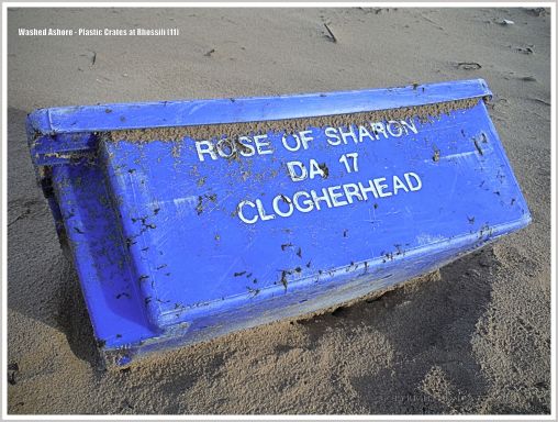 Blue plastic flotsam crate with white writing on the beach