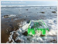 Green plastic crate washed up in sea foam