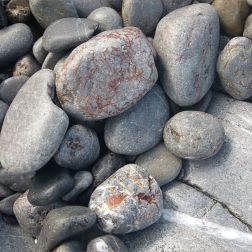 Pebbles at the water's edge in Pwll Du Bay
