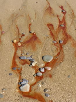 Red liquid draining from the beach at Whiteford Sands