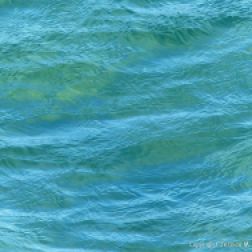 Texture and pattern of blue sea water over a yellow sandy shore