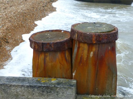 Rust-stained wooden upright post in a seashore groyne