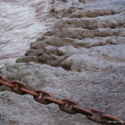 Rusty mooring chain and muddy river bank
