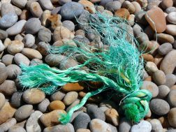 Green knotted rope washed up on a pebble beach