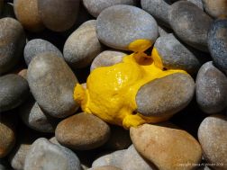 Yellow paint spilt on a pebble beach