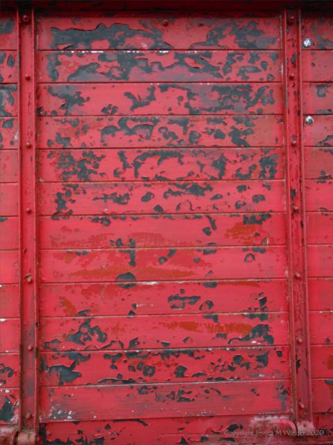 Flaking red paint on a piece of wooden agricultural equipment