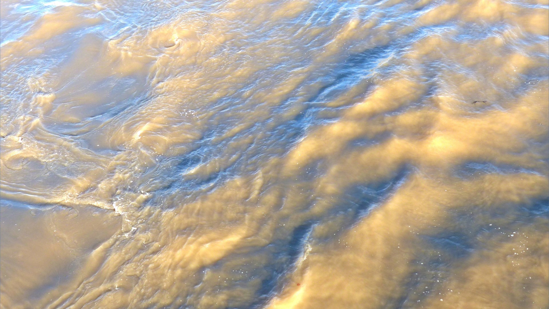 Swirling river water immediately water downstream of a bridge