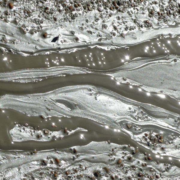 Pattern and texture of liquid mud flowing over beach shingle after land slip.